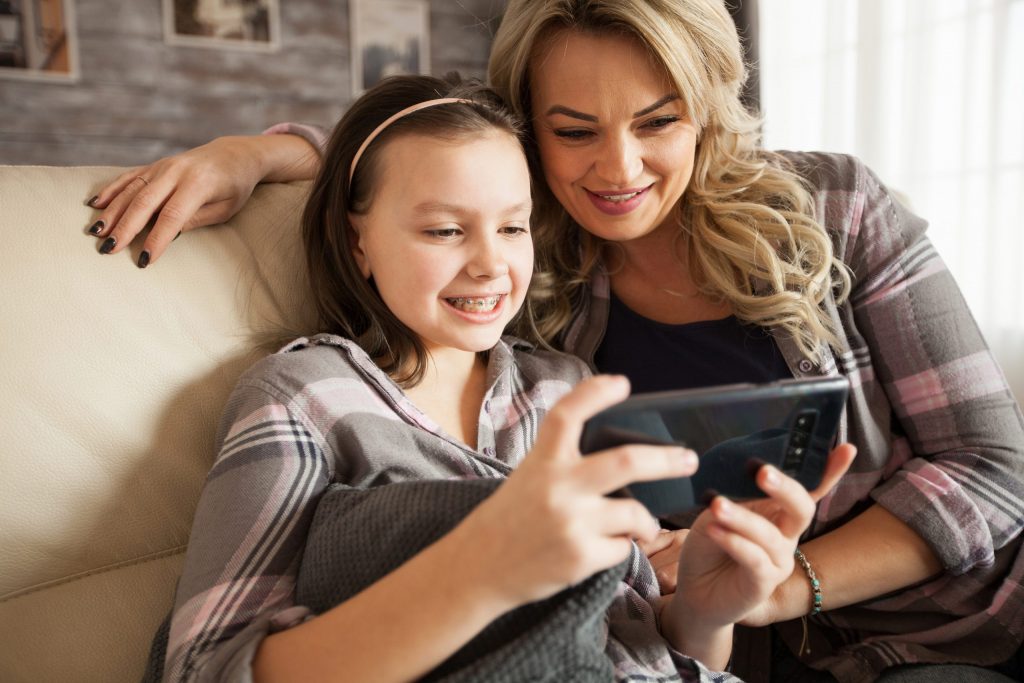 Mom and daughter spending time looking at TikTok videos on a smart phone.